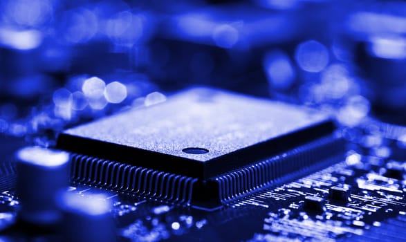 close-up chip on circuit board with selective focus, blue toned