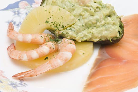 Avocado salad decorated with prawns, a slice of pineapple and a slice of salmon.