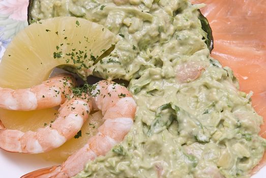 Avocado salad decorated with prawns, a slice of pineapple and a slice of salmon.