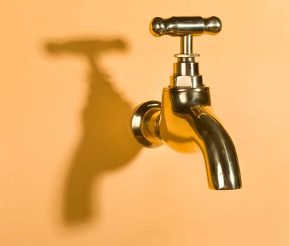 close-up gold faucet in orange wall