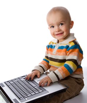 smiling little boy typing on laptop, isolated on white