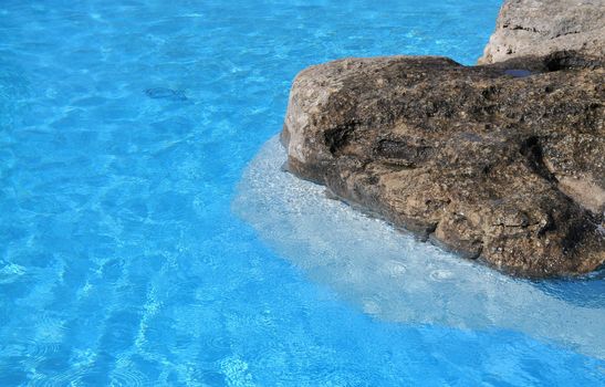 a rock in a crystal clear blue lagoon