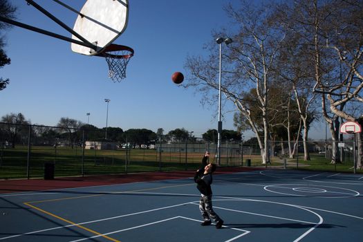 Young girl making a hook shot while practicing basketball