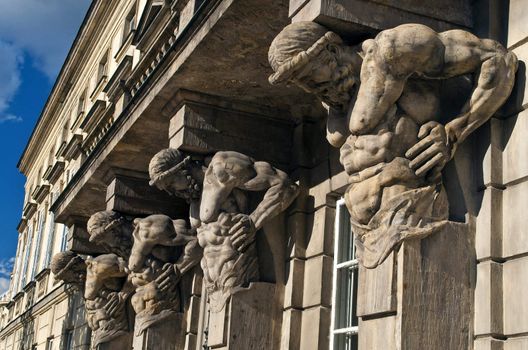 Columns, strong men statues holding a building.