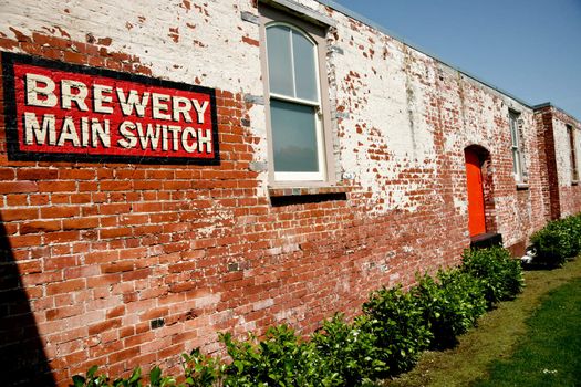 Brick wall of old brewery building, with sign.