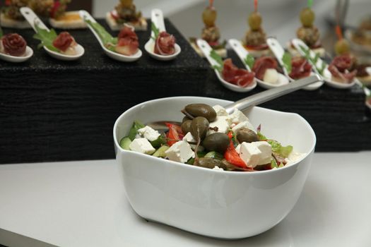 cup of Greek salad with feta cheese, fresh herbs, olives for a buffet