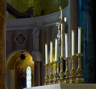 Set of ornate carved candlesticks on altar illuminated by sunlight with the darker alcoves of the church behind