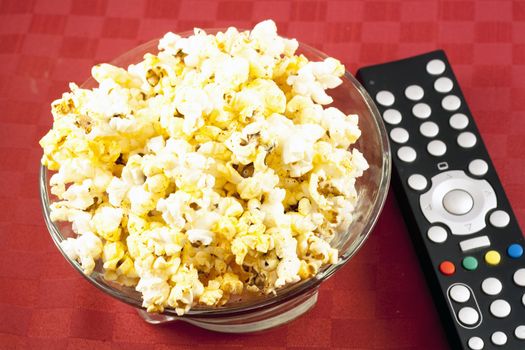 Bowl of popcorn on the table and remote control for TV