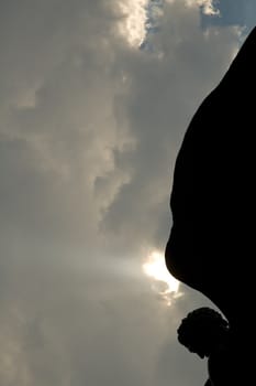 black silhouette of angel sculpture, dark sky in background