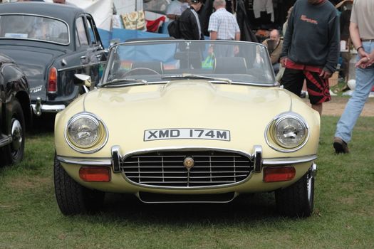 small yellow vintage sports car shown at a car show