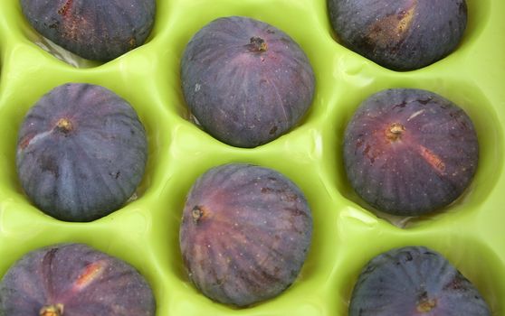 ripe fresh figs in green packaging background
