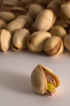 Salted pistachios  on white background, one in foreground, distance blur