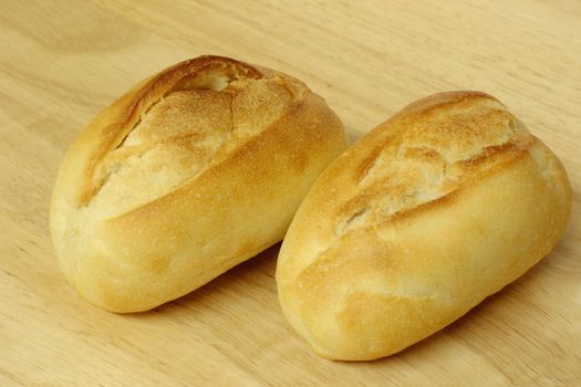 fresh baked bread rolls on a wooden bread board