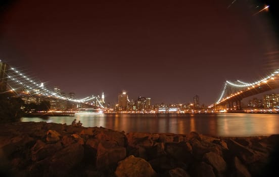 brooklyn and manhattan bridge night photo, rocks in foreground, star filter used to bring up the lights