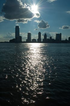 Jersey City viewed from New York, close to World Financial Center, sun reflection in water