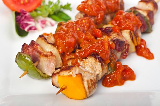 shashlik on a plate with a tomato and salad leaf