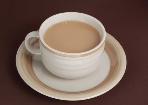 beige cup filled with milk coffee, brown background