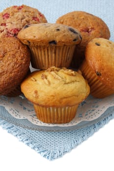 bunch of fresh muffins on a plate place over blue tablecloth