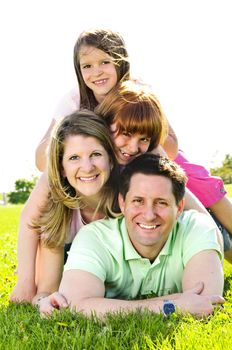 Portrait of happy family of four laying on grass at the park