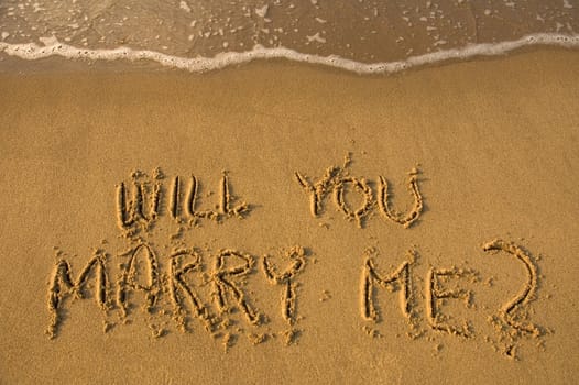 will you marry me written in sand, water approaching