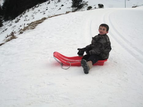 boy riding sledge in Pyrenean mountains, south France