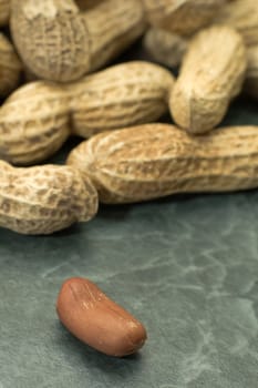 several closed peanuts shells, one peanut in focus in foreground
