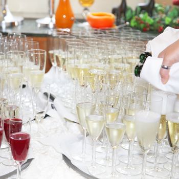  Many of champagne glasses on a table and be filled by a waiter
 
