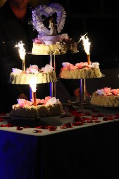 tiered wedding cake with candles and fireworks on a table
