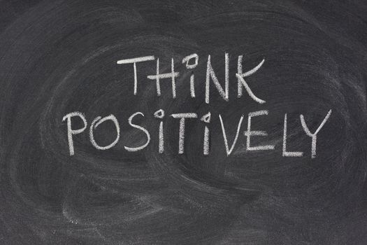 think positively slogan handwritten with white chalk on blackboard with strong eraser smudges