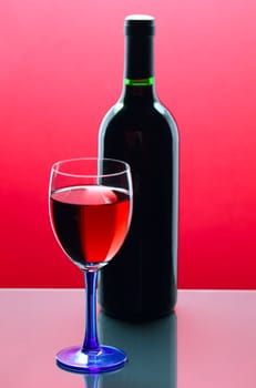 red wine glass with bottle in background