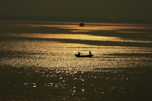 Silhouette of a filshing boat in lake at sunset