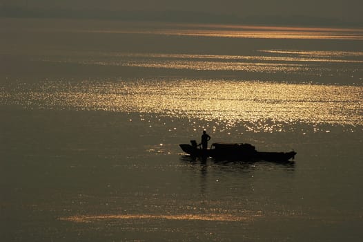 Silhouette of a filshing boat in lake at sunset