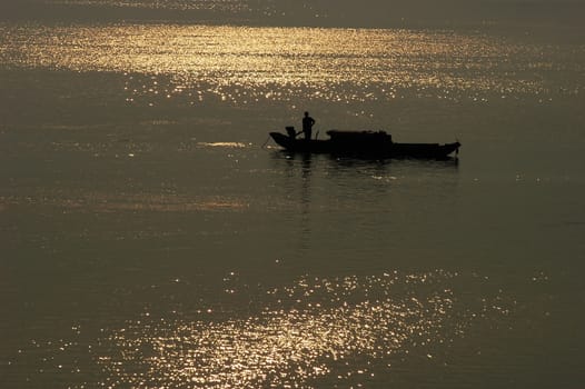 Silhouette of a filshing boat in lake at sunset
