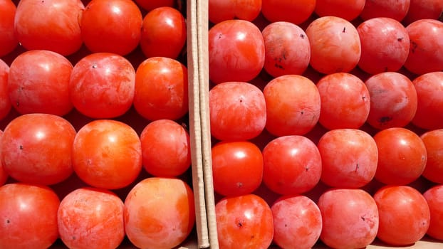 Closeup view of a pile of red persimmon fruits in autumn