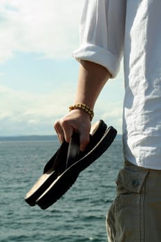 A man carrying sandals on the beach