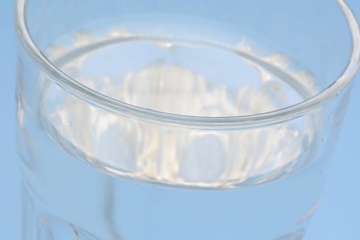 A close up of a glass of water with blue background