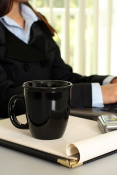 A businesswoman working in the office with a cup of coffee