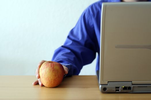 Businessman working on a laptop and holding an apple