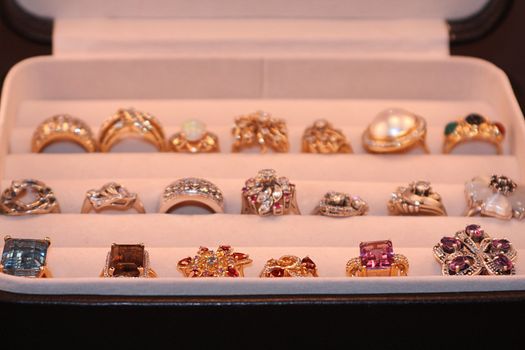 Open jewelry box with an assortment of diamond and gemstone gold rings.