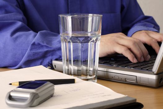 Businessman working on a laptop with a glass of water