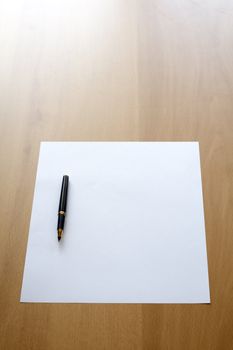 Blank white business paper and a pen on a table