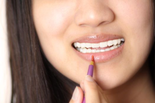 A woman applying lip gloss/lipstick