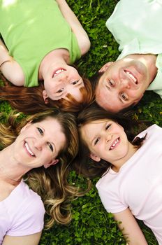 Portrait of happy family laying  on grass looking up heads together