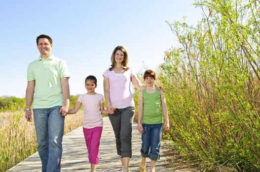 Portrait of happy family of four walking on boardwalk