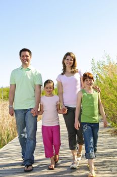 Portrait of happy family of four walking on boardwalk
