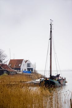 Fishing village and boat at the lake on dark, cloudy and rainy day in winter