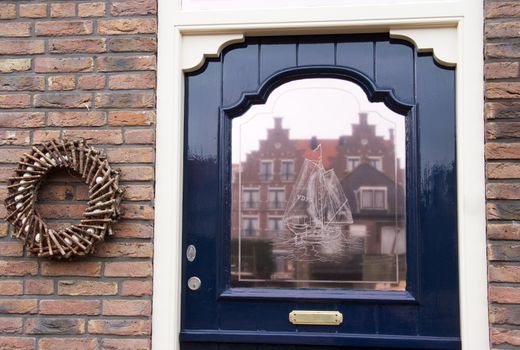 Frontdoor with engraved glass window and reflection of old Dutch houses