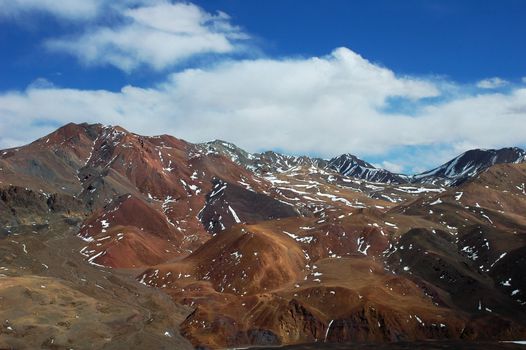Landscape of red mountains dotted by snow in winter