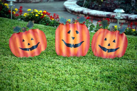 Three corrugated metal faces that look like pumpkins