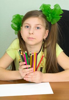Girl with color pencils in hands and a sheet of paper